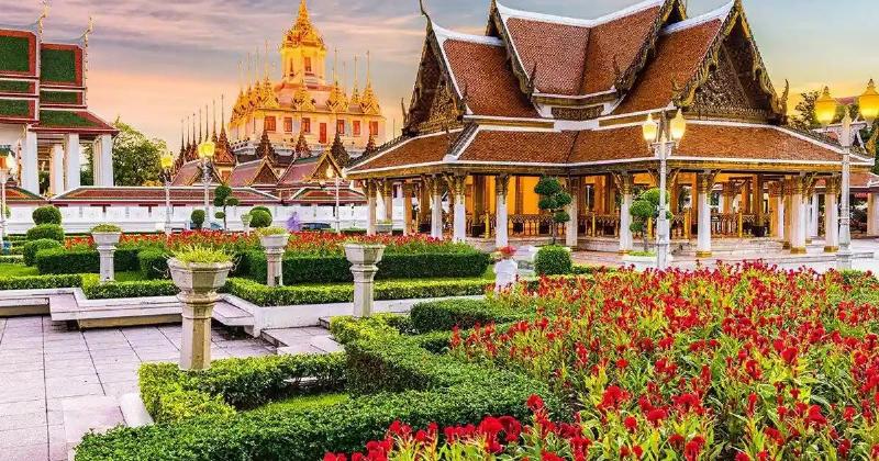 Khung cảnh đường phố Bangkok trong một cơn mưa rào nhiệt đới, người đi bộ trú mưa, xe cộ di chuyển chậm, mặt đường ướt át.