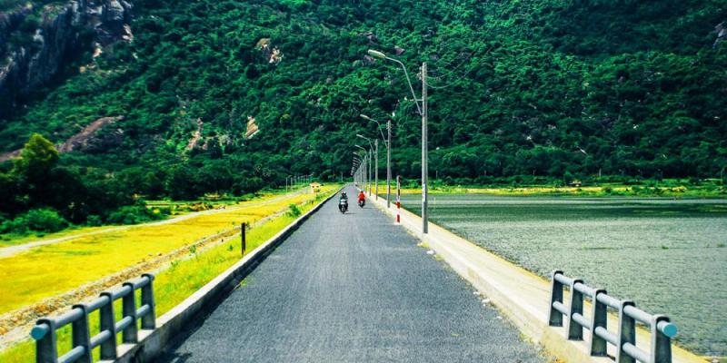Du khách vui vẻ chụp ảnh kỷ niệm tại hồ Tà Pạ với phong cảnh núi đá và hồ nước phía sau